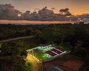 Aerial view of a villa complex at dusk in Dominical surrounded by trees and a winding road.