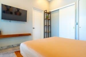 Ocean-view condo bedroom with TV, minimalist decor and warm lighting.