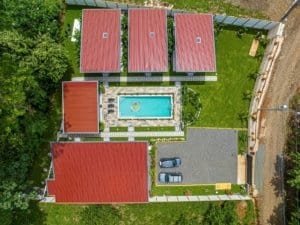 Aerial view of a villa complex with red roofs, central pool, and surrounding green lawn.