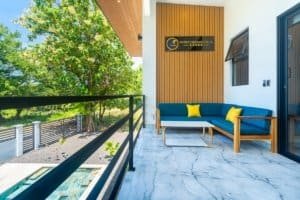 Two‑seat blue and yellow outdoor seating with wooden wall paneling and balcony railing in Dominical.