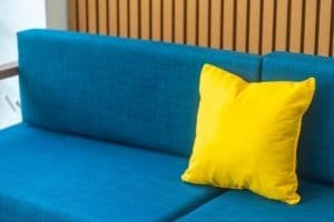 Blue sofa with yellow accent pillow in a modern turquoise living space.