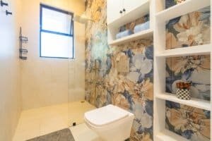 Ocean view condo bathroom with floral wallpaper and open shower.