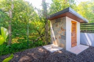Stone exterior utility hut surrounded by lush Costa Rica forest and gravel path.