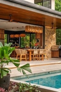 Outdoor dining area with hanging lights overlooking pool and tropical greenery.