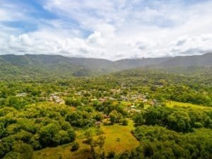 Dominical real estate: lush hillside town with green valley and distant hills.