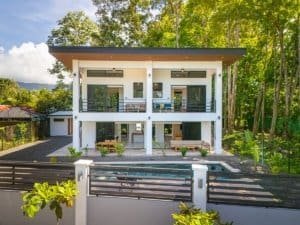 Two-story modern condo with balcony and pool in lush jungle setting.
