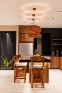 Modern kitchen with wooden island and hanging rattan light in tropical home.
