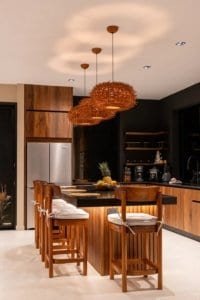 Modern kitchen in a jungle home with wooden island and hanging pendant lights.