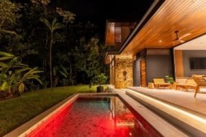Luxurious villa with illuminated red pool and outdoor seating at night.