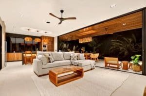 Luxurious living room with neutral sofa, wooden accents, and glass walls overlooking lush jungle.