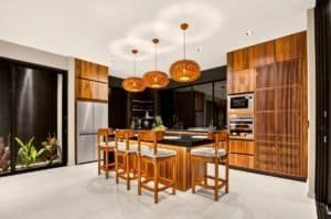 Luxurious jungle home kitchen with wooden cabinetry and island bar in Costa Rica.