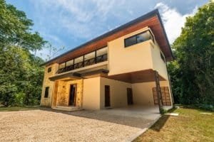 Dominical-style luxury jungle home with wood accents, ample balcony, and surrounding tropical trees.