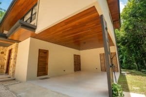 Modern Costa Rica home with wooden overhang, covered patio and lush greenery.