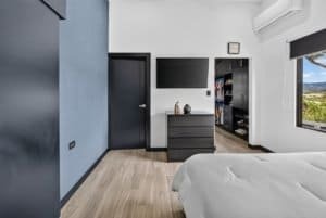 Contemporary bedroom with mountain views, flat-screen TV, and minimalist decor.