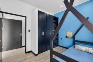 Contemporary bedroom with blue wall, black furniture, and mountain views.