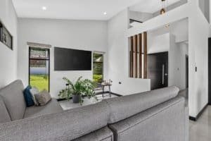 Contemporary living room with large TV, gray sofa, and mountain views.