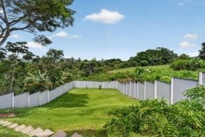 Large green backyard with mountain views and white fence in Dominical.