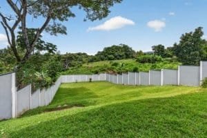 Large green backyard with mountain views and white fence in Dominical.
