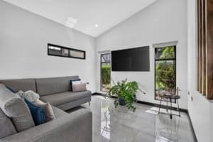 Bright modern living room with large TV, gray sofas, and mountain views.