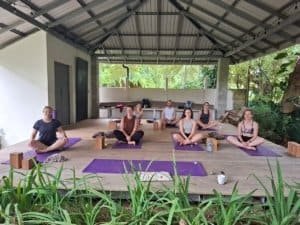 Group of people practicing yoga outdoors on a covered deck in Dominical, Costa Rica.