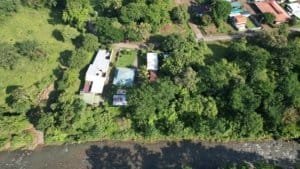 Aerial view of riverfront retreat with guest rooms and lush greenery in Dominical.