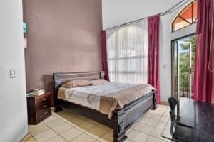 Bright bedroom with large window and balcony overlooking mountains.