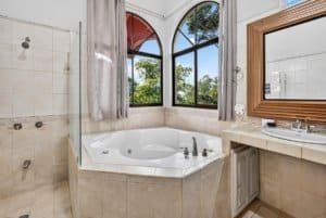 Spacious bathroom with a large bathtub and panoramic mountain view windows.