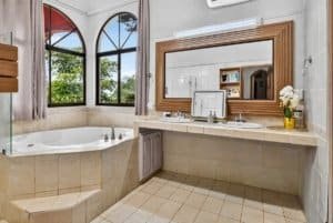 Bright bathroom with large windows and mountain scenery in Dominical, Costa Rica.