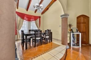 Elegant dining room with large window, red curtains, and wooden furniture.