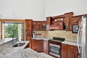 Kitchen with wooden cabinets, granite countertops, and mountain view through window.