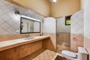 Large bathroom with double sink, mirror, and toilet in Dominical, Costa Rica.