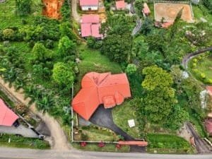 Aerial view of a large home with red roof, surrounded by lush greenery in Costa Rica.