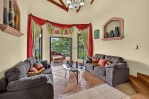 Bright living room with large glass doors, colorful curtains, and mountain scenery.