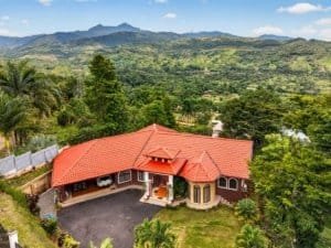 Large home with red roof and mountain scenery in Dominical, Costa Rica.
