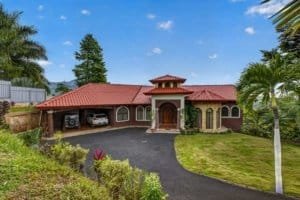 Large house with red roof, surrounded by lush greenery and palm trees in Costa Rica.